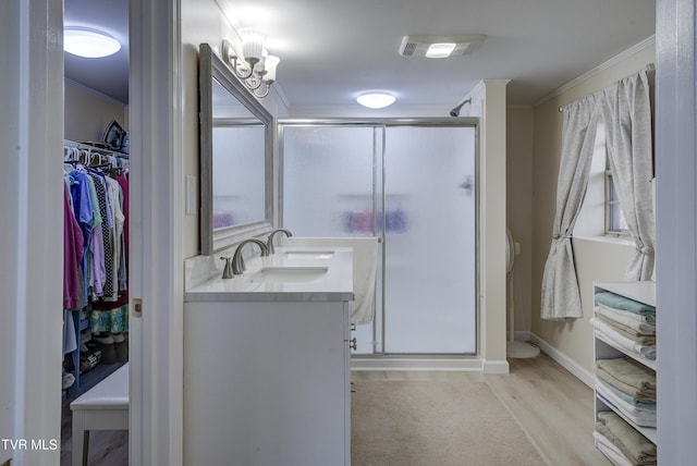 bathroom with a sink, double vanity, a shower stall, and crown molding