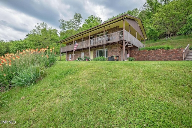 rear view of property featuring a yard, brick siding, and a wooden deck