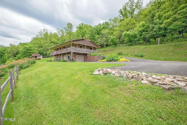 view of front of house featuring a garage, a view of trees, a front lawn, and fence