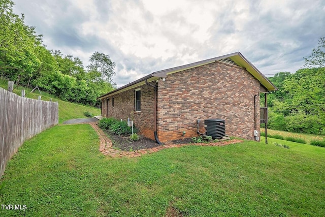 view of side of property with fence, cooling unit, a lawn, and brick siding