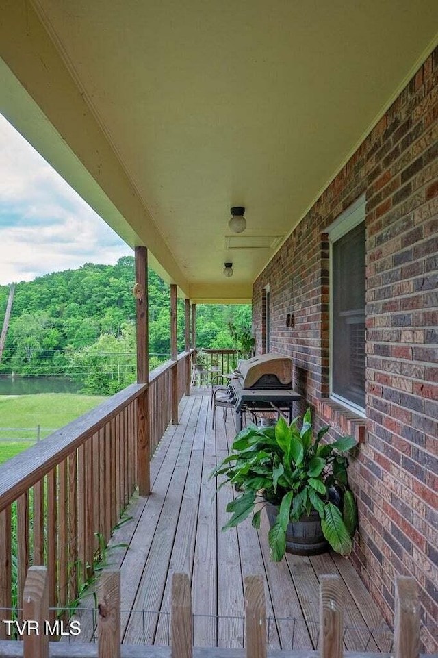 wooden deck featuring area for grilling and a wooded view