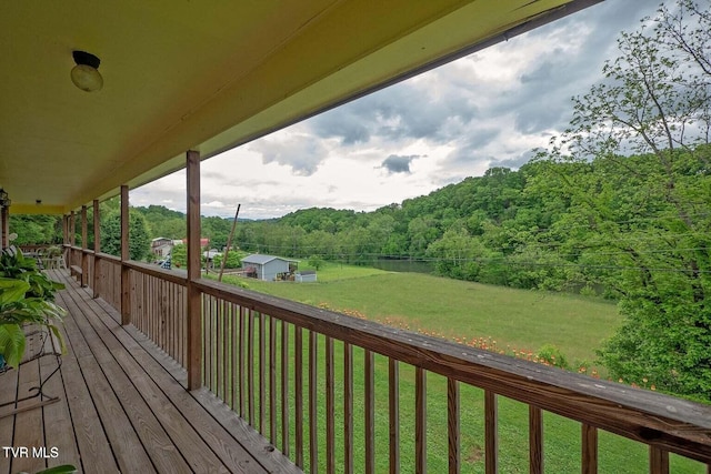 wooden terrace featuring a lawn and a wooded view