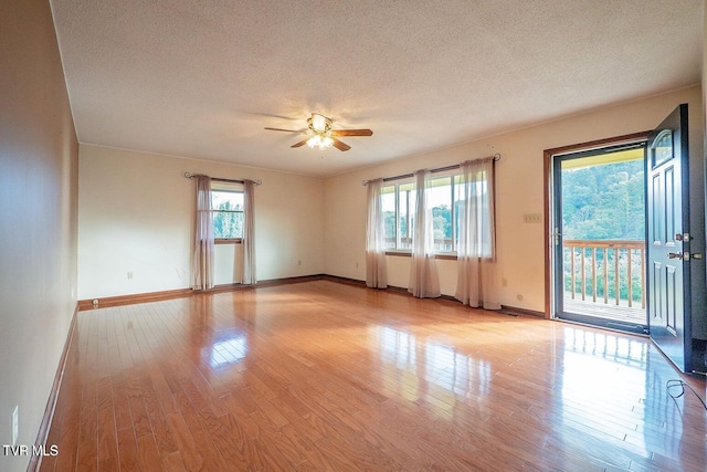 spare room featuring light wood-style flooring, a textured ceiling, and baseboards