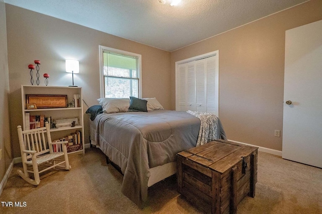 bedroom with a closet, baseboards, light colored carpet, and a textured ceiling