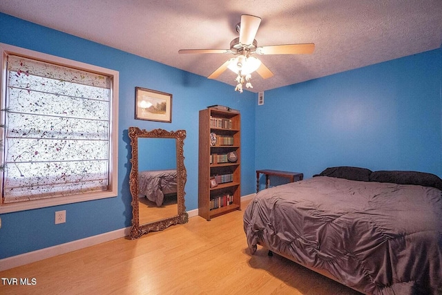 bedroom featuring light wood-style flooring, a ceiling fan, baseboards, and a textured ceiling