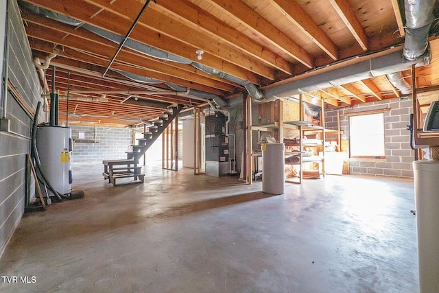 below grade area with concrete block wall, heating unit, electric water heater, and stairs