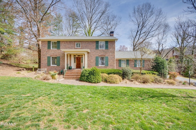 view of front of house with brick siding, a chimney, and a front lawn