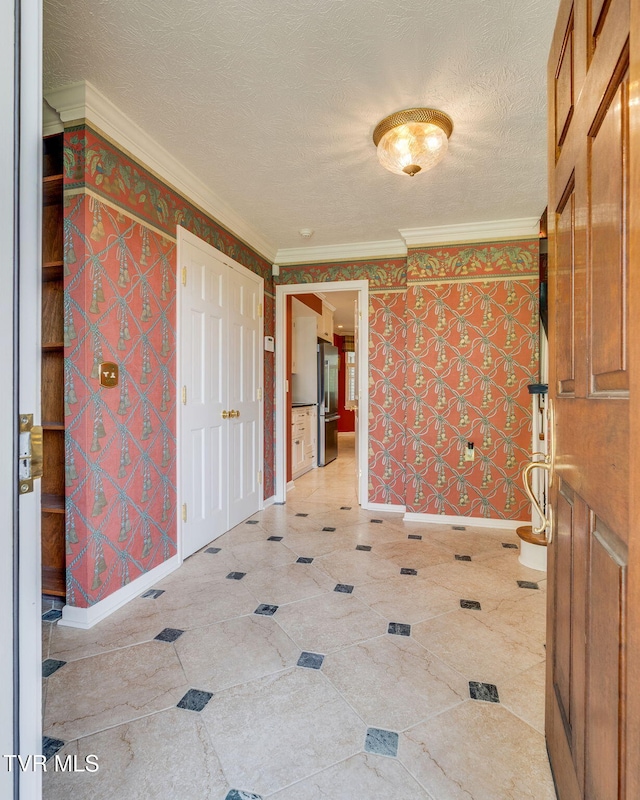 interior space with a textured ceiling, ornamental molding, and baseboards
