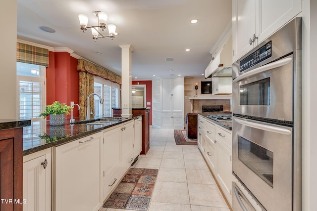 kitchen with a sink, double oven, dark stone counters, white cabinetry, and decorative backsplash