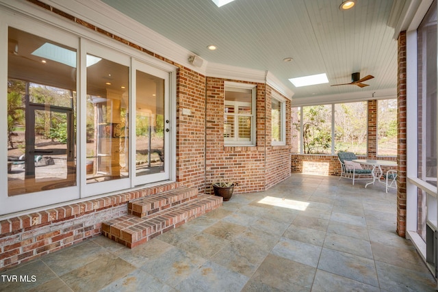 unfurnished sunroom with entry steps, ceiling fan, and a skylight