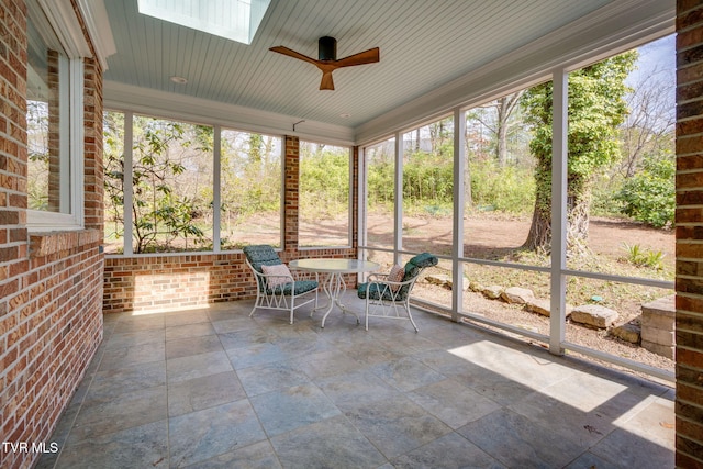 unfurnished sunroom with a ceiling fan, a skylight, and a wealth of natural light