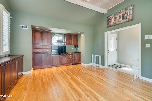 kitchen featuring visible vents, baseboards, beverage cooler, light wood-style floors, and vaulted ceiling with beams