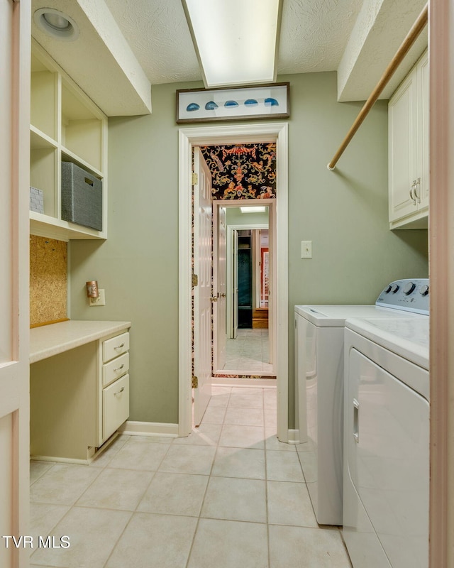 laundry room featuring washing machine and dryer, light tile patterned flooring, baseboards, a textured ceiling, and cabinet space