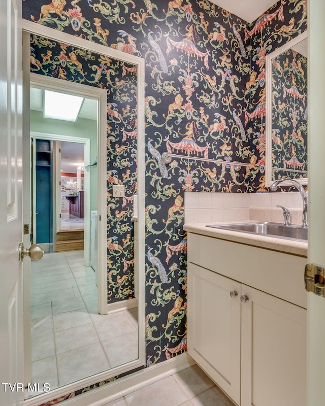 bathroom featuring baseboards, wallpapered walls, tile patterned floors, and vanity