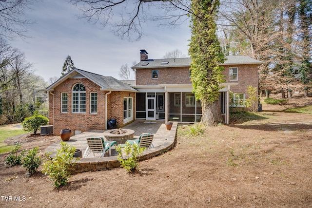rear view of house with a chimney, a patio area, a sunroom, brick siding, and an outdoor fire pit