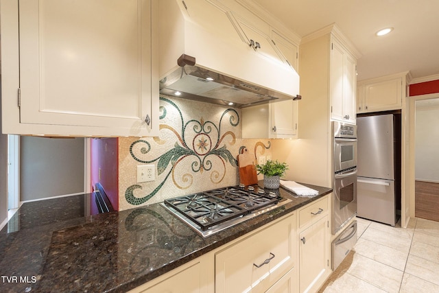 kitchen featuring exhaust hood, backsplash, appliances with stainless steel finishes, dark stone countertops, and a warming drawer