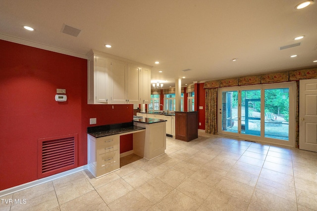 kitchen featuring dark countertops, ornamental molding, white cabinetry, and visible vents
