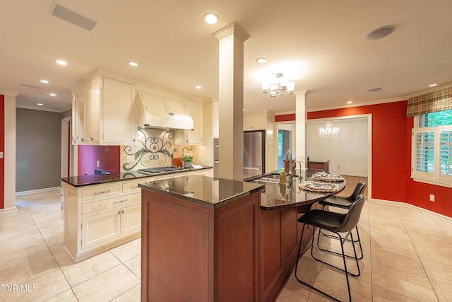 kitchen with decorative columns, visible vents, a sink, freestanding refrigerator, and ornamental molding