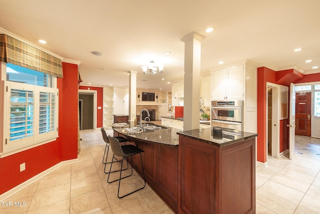 kitchen with crown molding, recessed lighting, white cabinetry, a sink, and dark stone countertops