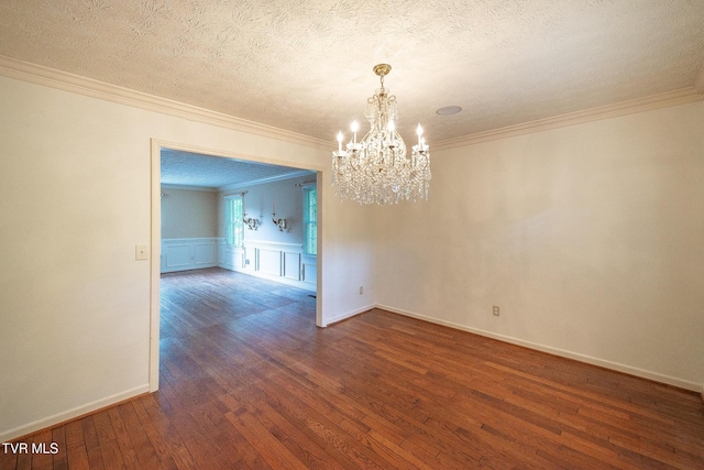 unfurnished dining area featuring an inviting chandelier, crown molding, wood finished floors, a textured ceiling, and a wainscoted wall