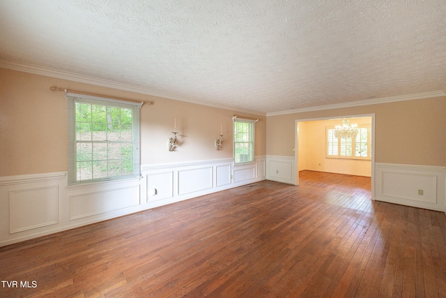 spare room with wood-type flooring, a chandelier, wainscoting, and plenty of natural light