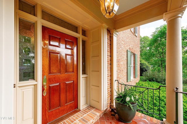 entrance to property featuring a porch and brick siding