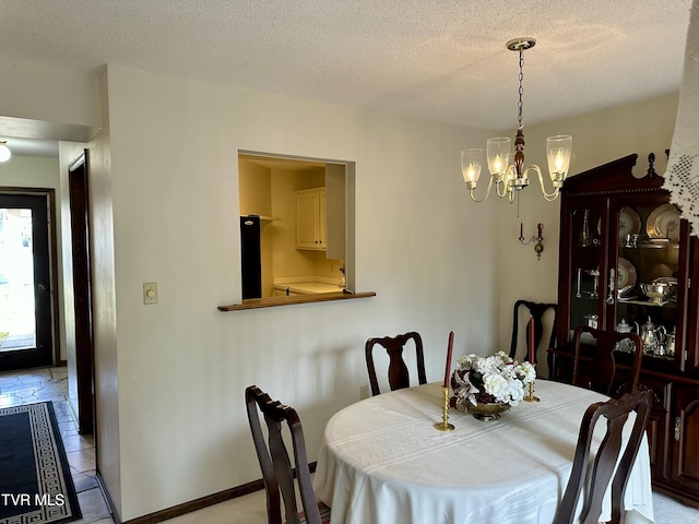 dining space with an inviting chandelier, baseboards, and a textured ceiling