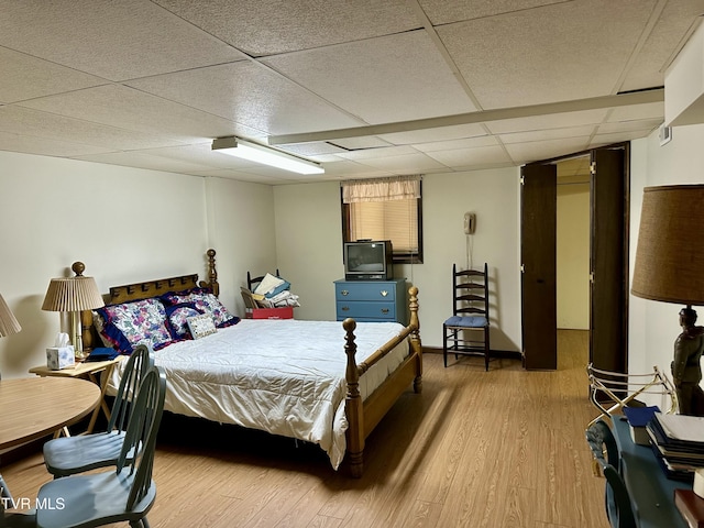 bedroom featuring a drop ceiling and light wood-style flooring