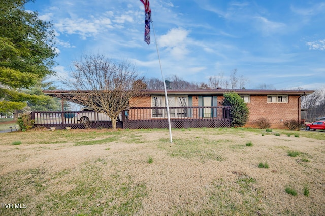 back of property featuring brick siding, a lawn, and a wooden deck