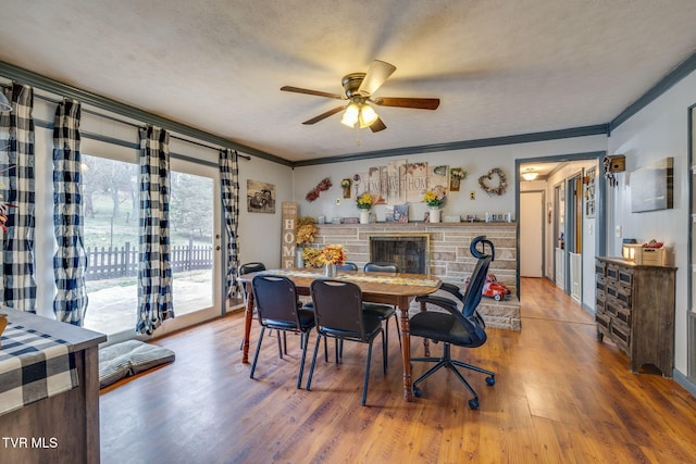 dining space featuring a textured ceiling, wood finished floors, a ceiling fan, and ornamental molding