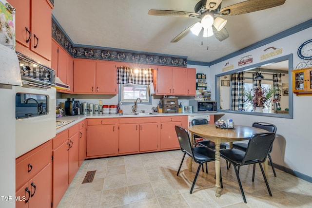 kitchen with stainless steel microwave, light countertops, ornamental molding, white oven, and a sink