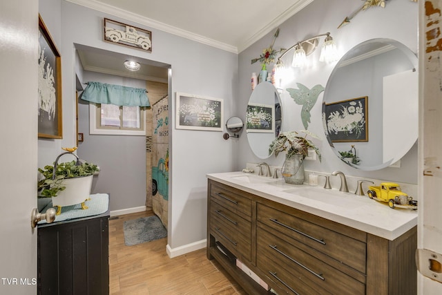 bathroom featuring a sink, baseboards, wood finished floors, and ornamental molding