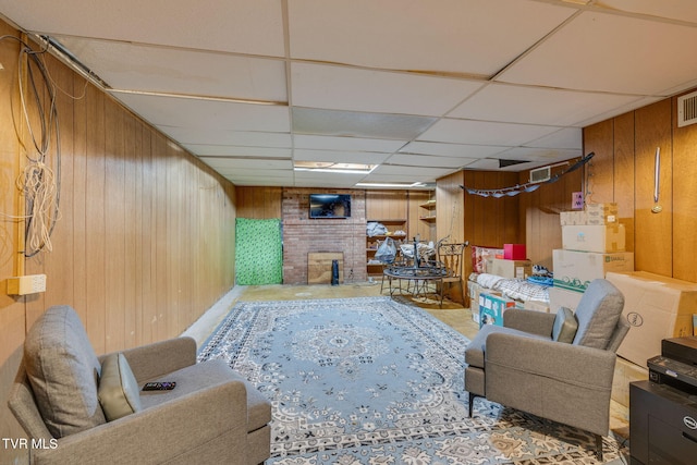 living area featuring a drop ceiling, wood walls, and visible vents