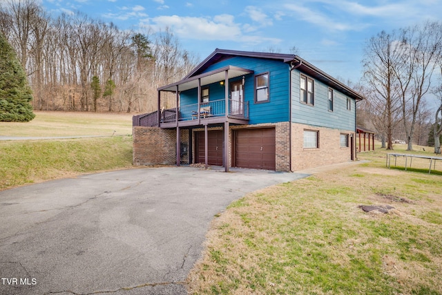 view of front of property featuring brick siding, a trampoline, aphalt driveway, a front yard, and a garage