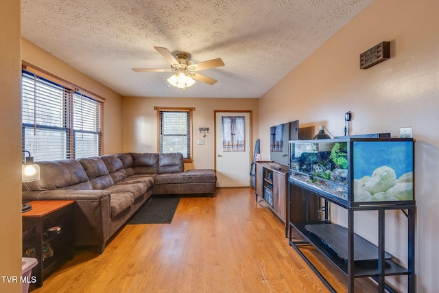 living room with a textured ceiling, light wood-type flooring, and a ceiling fan