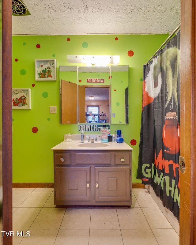 bathroom with tile patterned floors, curtained shower, a textured ceiling, baseboards, and vanity