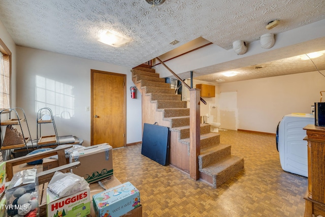 interior space featuring baseboards, washer / clothes dryer, and a textured ceiling