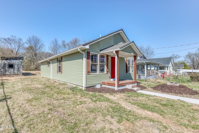 view of front of property featuring covered porch, an outdoor structure, and a front lawn