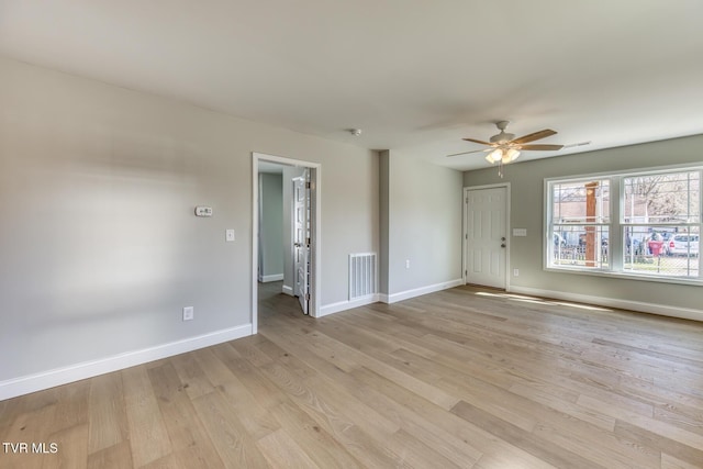 unfurnished room featuring a ceiling fan, light wood-style floors, visible vents, and baseboards