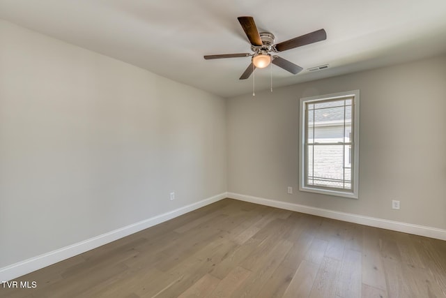 spare room with visible vents, ceiling fan, baseboards, and wood finished floors