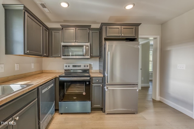 kitchen with baseboards, visible vents, light wood finished floors, recessed lighting, and stainless steel appliances