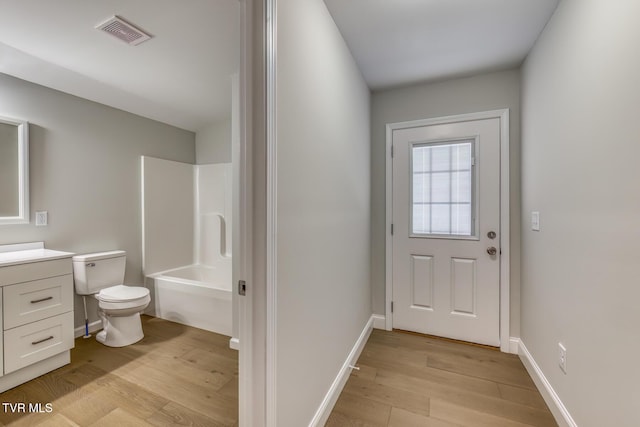 interior space with visible vents, toilet, vanity, and wood finished floors