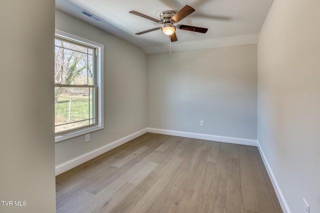 unfurnished room with a ceiling fan, visible vents, wood finished floors, and baseboards