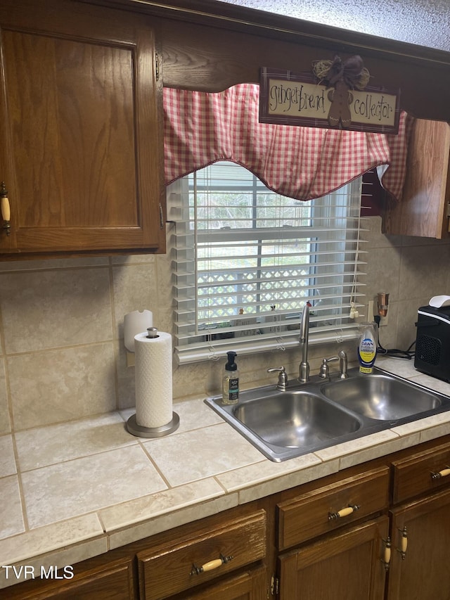 kitchen with decorative backsplash, light countertops, and a sink