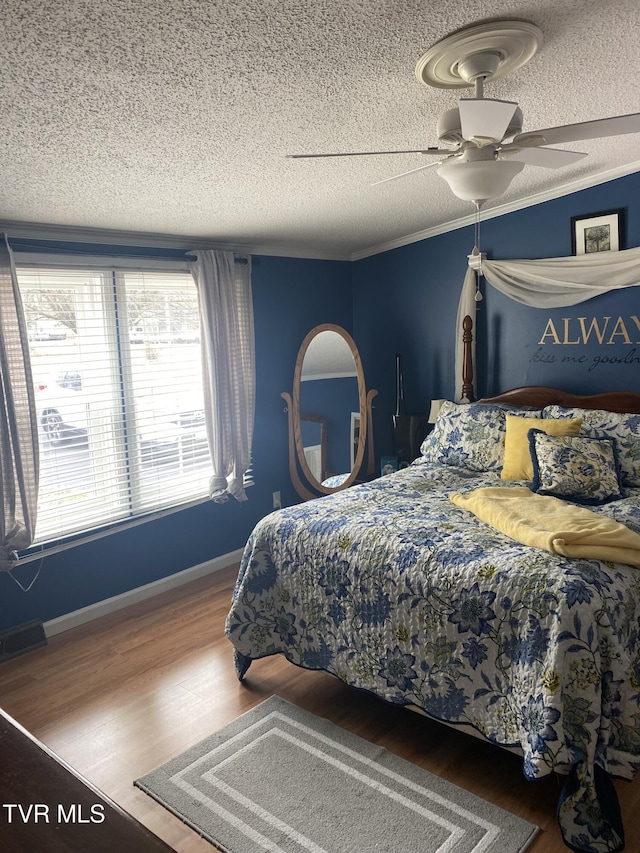 bedroom featuring visible vents, crown molding, ceiling fan, and wood finished floors