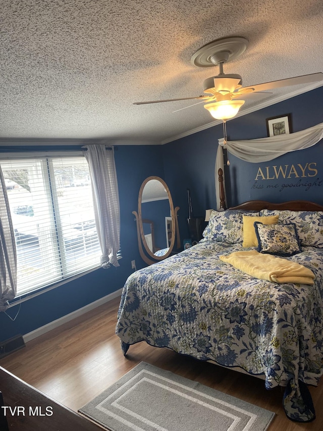 bedroom featuring crown molding, wood finished floors, and a textured ceiling