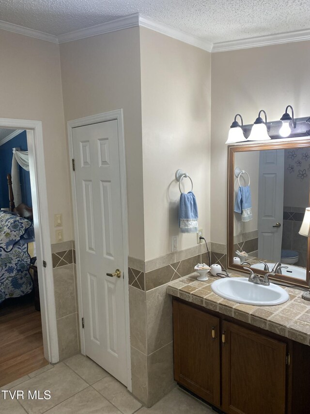 bathroom with tile patterned flooring, a textured ceiling, tile walls, and vanity