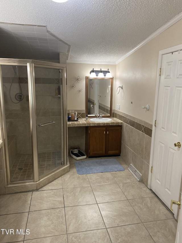 bathroom with visible vents, a shower stall, crown molding, a textured ceiling, and vanity