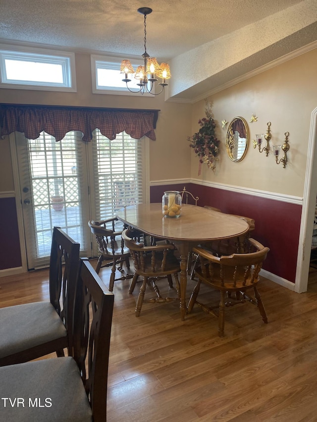 dining room with crown molding, baseboards, an inviting chandelier, wood finished floors, and a textured ceiling