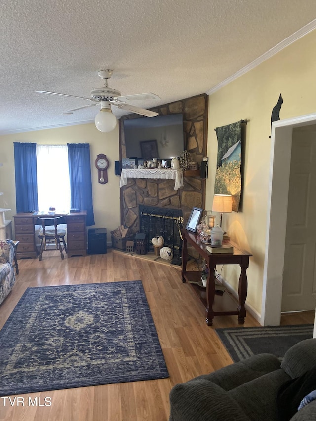 living area featuring ornamental molding, a fireplace, a textured ceiling, and wood finished floors